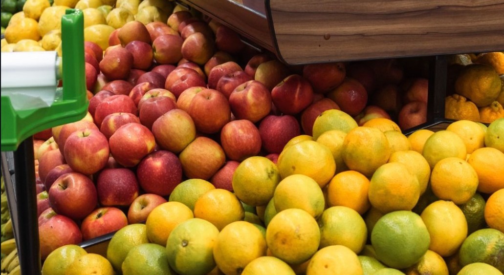Bancada de frutas do hortifrúti do Bom Demais, com maçãs, laranjas e limões